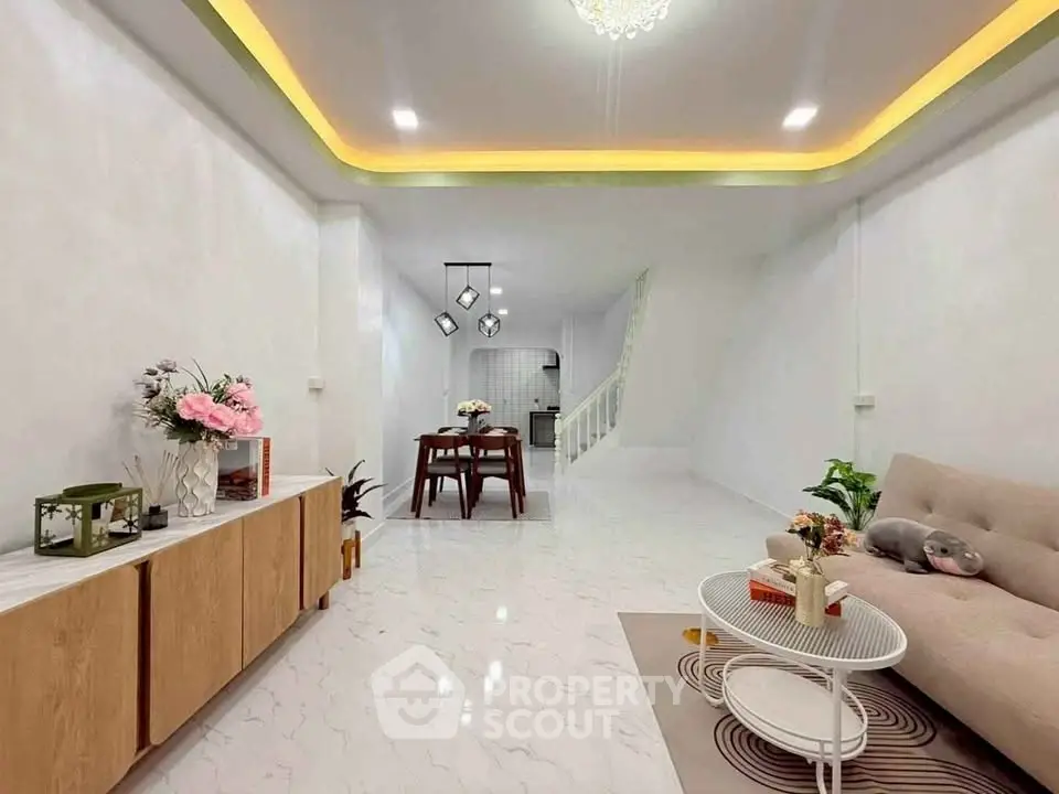 Modern living room with elegant decor and open dining area, featuring stylish lighting and sleek furniture.