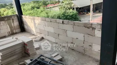 Construction site with unfinished brick wall and stacked materials, showcasing potential for development.