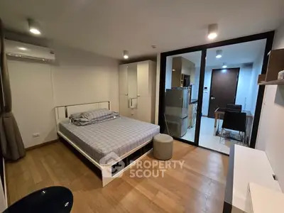 Modern bedroom with glass partition, wooden flooring, and minimalist decor in a stylish apartment.
