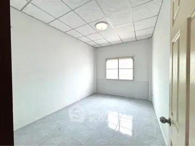 Spacious empty room with tiled floor and window, ideal for customization.
