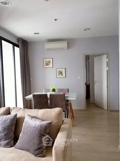 Modern living room with dining area, featuring neutral tones and stylish decor.