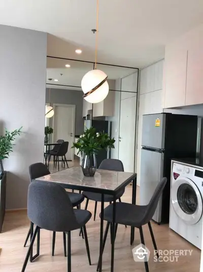 Modern open-plan kitchen and dining area with elegant pendant lighting, sleek appliances, and a cozy dining set, perfect for urban living.