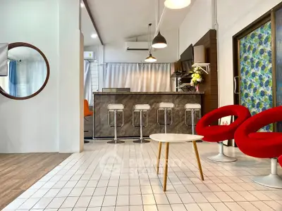 Modern open-plan living area with stylish bar counter and vibrant red chairs
