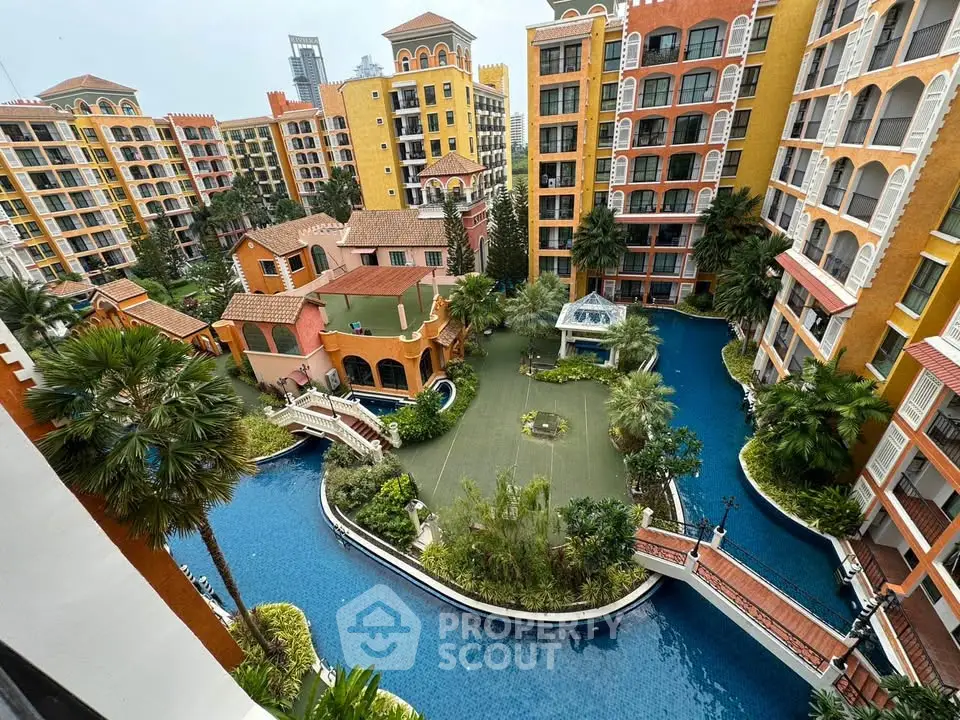 Stunning aerial view of luxurious apartment complex with lush gardens and serene pool area.