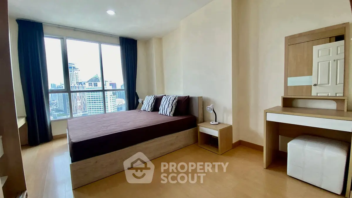 Modern bedroom with city view, featuring a cozy bed and stylish furniture.