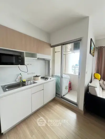Modern kitchen with sleek cabinetry and balcony view in a stylish apartment