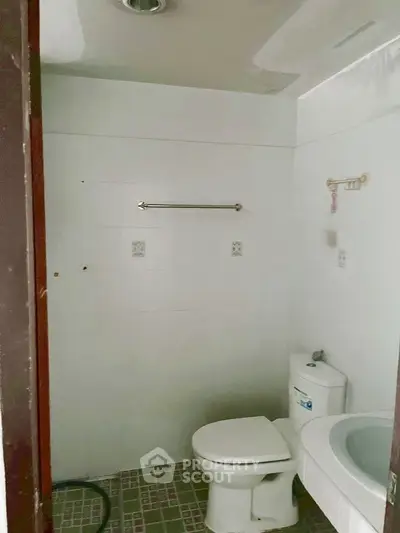 Simple bathroom with toilet, sink, and towel rack in a real estate property.