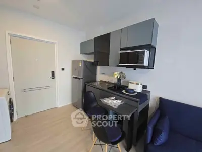 Modern compact kitchen with sleek cabinetry and dining area in a stylish apartment.