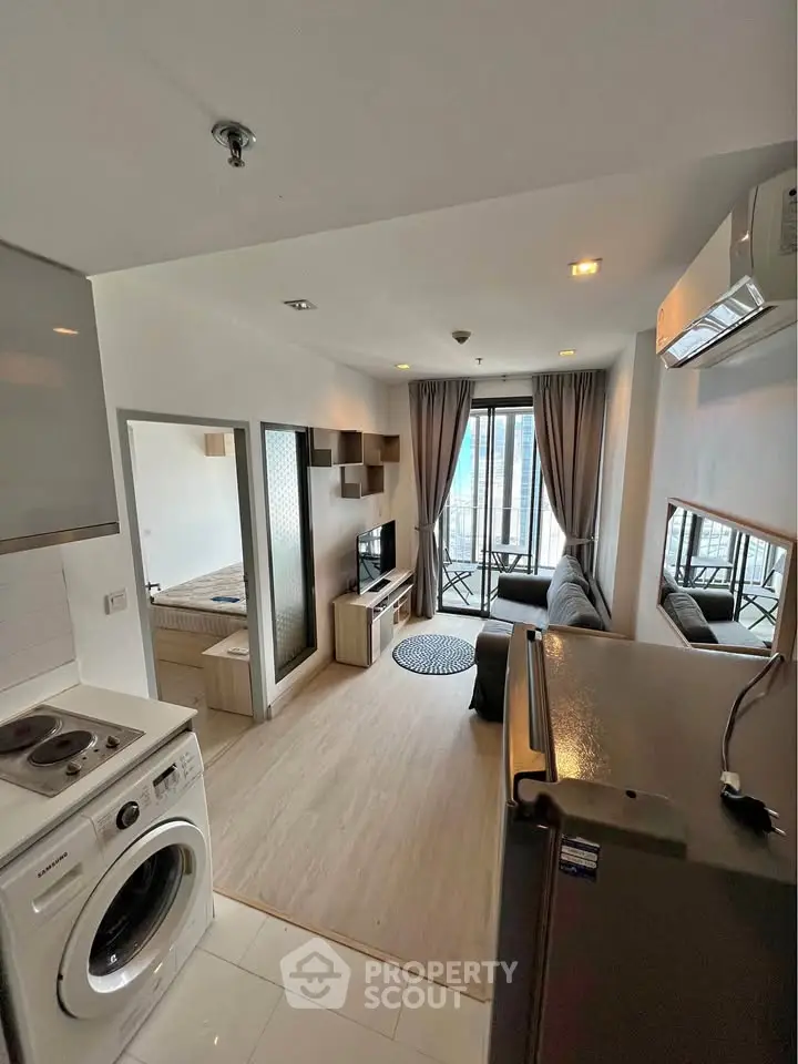 Modern apartment interior with open layout, featuring a cozy living room and compact kitchen area.