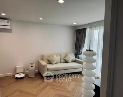 Modern living room with cozy sofa and stylish decor, featuring wooden flooring and natural light.
