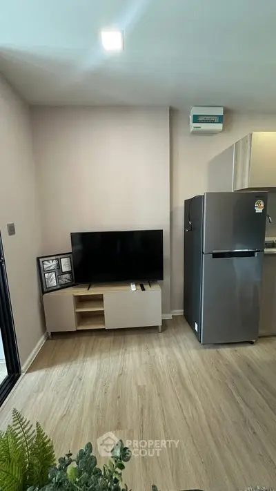 Modern living room with sleek TV setup and stainless steel fridge, perfect for contemporary urban living.