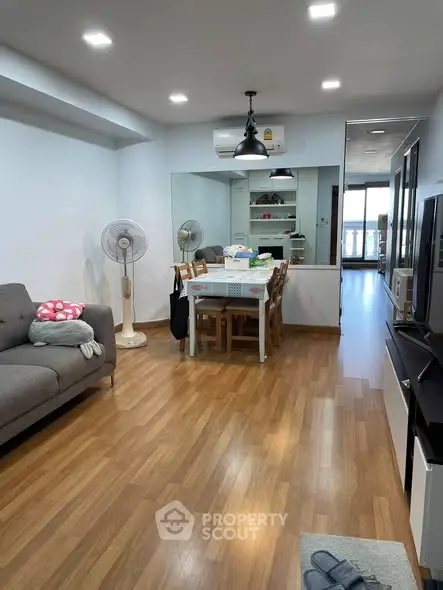 Spacious living room with wooden flooring and modern furniture in a cozy apartment.