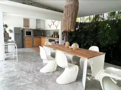 Stylish open-air kitchen with modern dining area and lush greenery