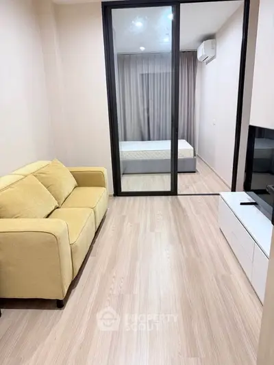 Modern apartment with cozy living room and bedroom separated by glass doors.