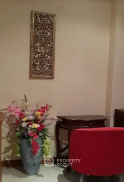 Elegant interior with decorative vase and red chair in cozy corner.