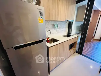Modern kitchen with sleek wooden cabinets and stainless steel fridge in stylish apartment