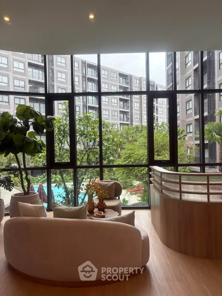 Luxurious living room with floor-to-ceiling windows overlooking a lush garden and pool area.
