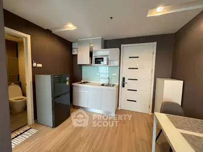 Modern compact kitchen with sleek appliances and wooden flooring in cozy apartment.