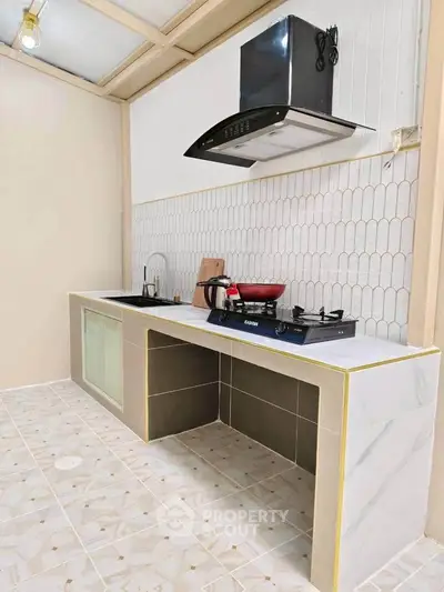 Modern kitchen with sleek countertops and gas stove, featuring stylish backsplash and ample storage space.