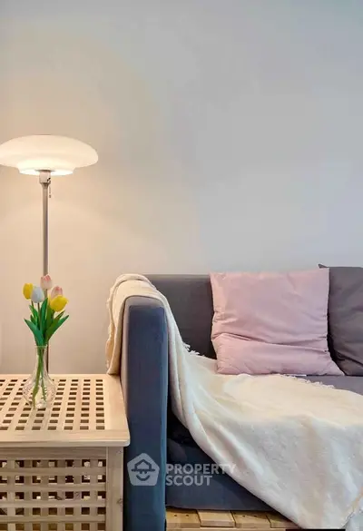 Cozy living room with stylish sofa, soft pillows, and elegant lamp for a warm ambiance.