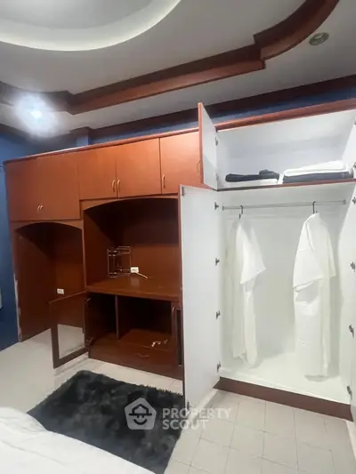 Spacious bedroom with built-in wooden wardrobe and modern ceiling design.