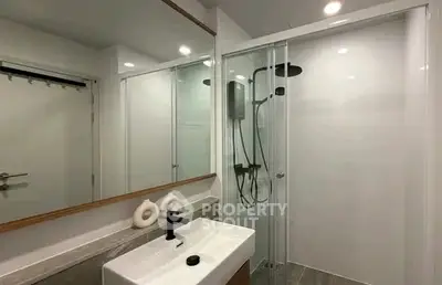 Modern bathroom with sleek shower and stylish sink in contemporary apartment.
