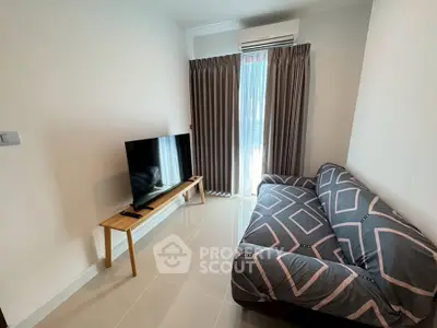 Cozy living room with modern sofa and flat-screen TV, perfect for relaxation.