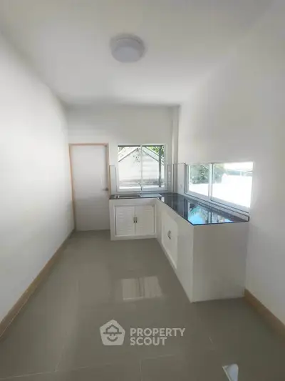 Modern minimalist kitchen with sleek countertops and ample natural light.