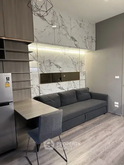 Modern living room with sleek design, featuring a gray sofa, marble accents, and a compact dining area.