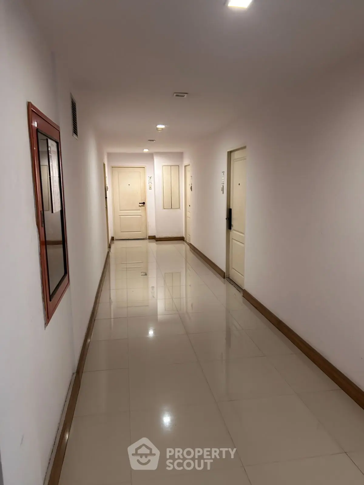 Spacious and well-lit apartment corridor with glossy tiled flooring.
