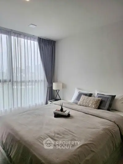 Modern bedroom with large window and stylish decor in a high-rise apartment.