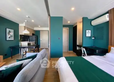 Modern open-plan living room and bedroom with stylish decor and teal accents