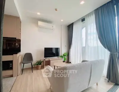Modern living room with natural light, cozy sofa, and sleek TV setup.