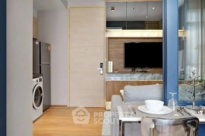Modern apartment interior with open kitchen and living area, featuring a washing machine and sleek decor.