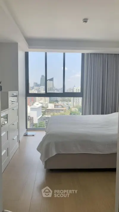 Modern bedroom with city view and large windows in high-rise apartment