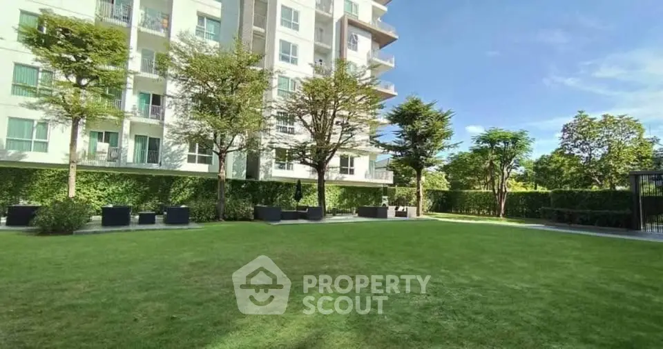 Spacious garden area with modern apartment building and lush greenery