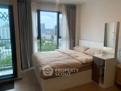 Modern bedroom with large windows offering city views, featuring a cozy bed and stylish decor.