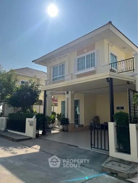 Charming two-story house with sunny exterior and gated entrance in a serene neighborhood.