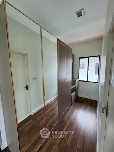 Modern bedroom with mirrored wardrobe and wooden flooring