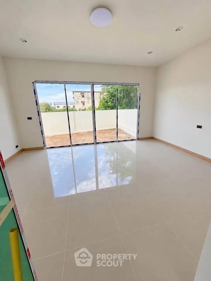 Spacious living room with large windows and balcony access, offering abundant natural light and serene views.