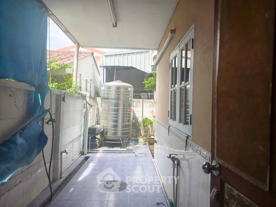 Charming outdoor utility area with water tank and tiled flooring, perfect for practical home use.