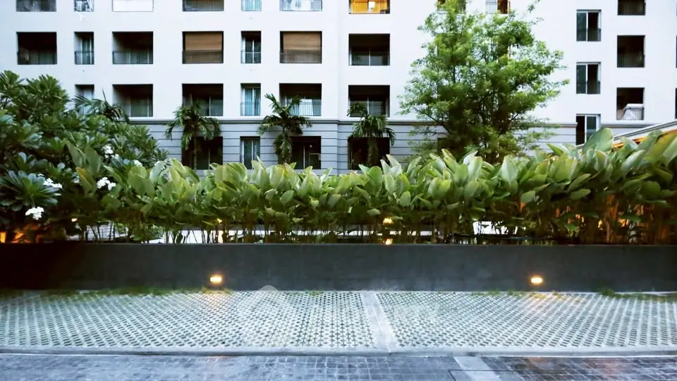 Modern apartment building with lush greenery and spacious courtyard.