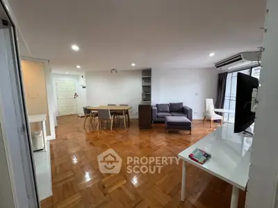 Spacious living room with wooden flooring and modern furniture in a bright apartment.