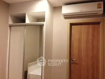 Modern bedroom with air conditioning and sliding closet doors, showcasing a cozy and efficient design.