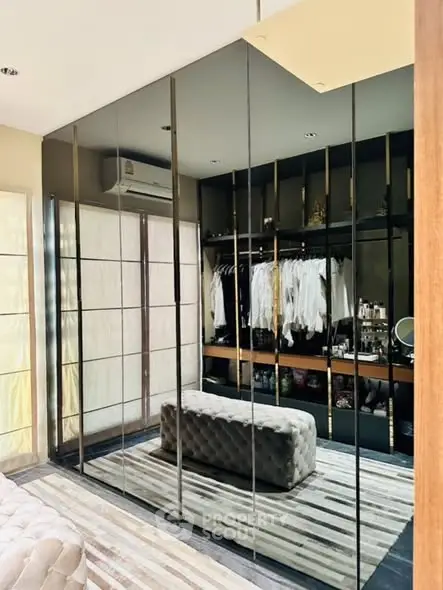 Luxurious walk-in closet with mirrored doors and elegant seating
