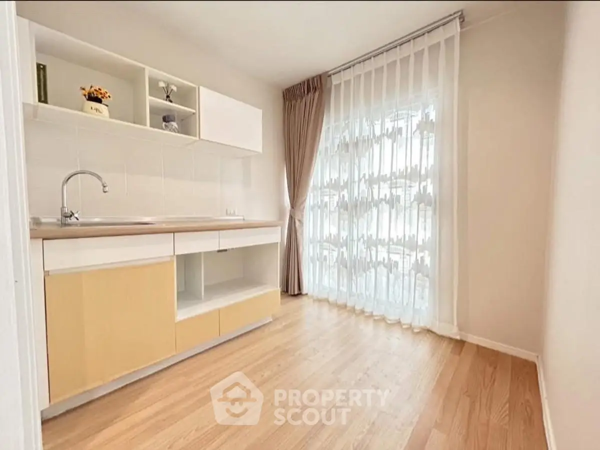 Bright kitchen with wooden flooring and large window, perfect for cozy cooking.