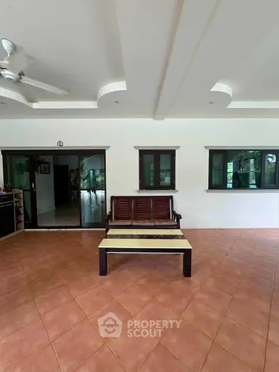 Spacious living room with elegant tiled flooring and stylish wooden furniture, perfect for relaxation and gatherings.