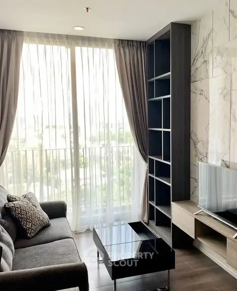 Modern living room with floor-to-ceiling windows and stylish furniture in a high-rise apartment.