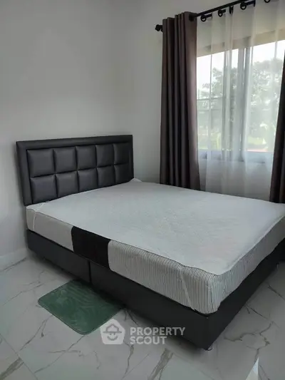 Modern bedroom with stylish bed and large window offering natural light.