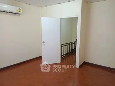 Spacious room with wooden flooring and air conditioning, ideal for versatile use.